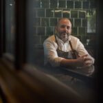 Chef head shot relaxing on sofa in restaurant lounge.