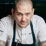 

Gourmet chef smiling in restaurant kitchen.
