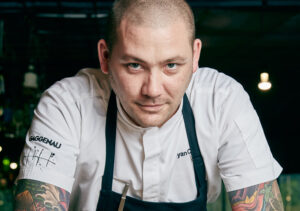 

Gourmet chef smiling in restaurant kitchen.
