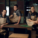 Cheerful barista team posing in coffee shop.