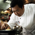 Professional chef holding kitchen tools for culinary portrait.