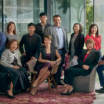 Group portrait of hotel managers at hotel entrance.