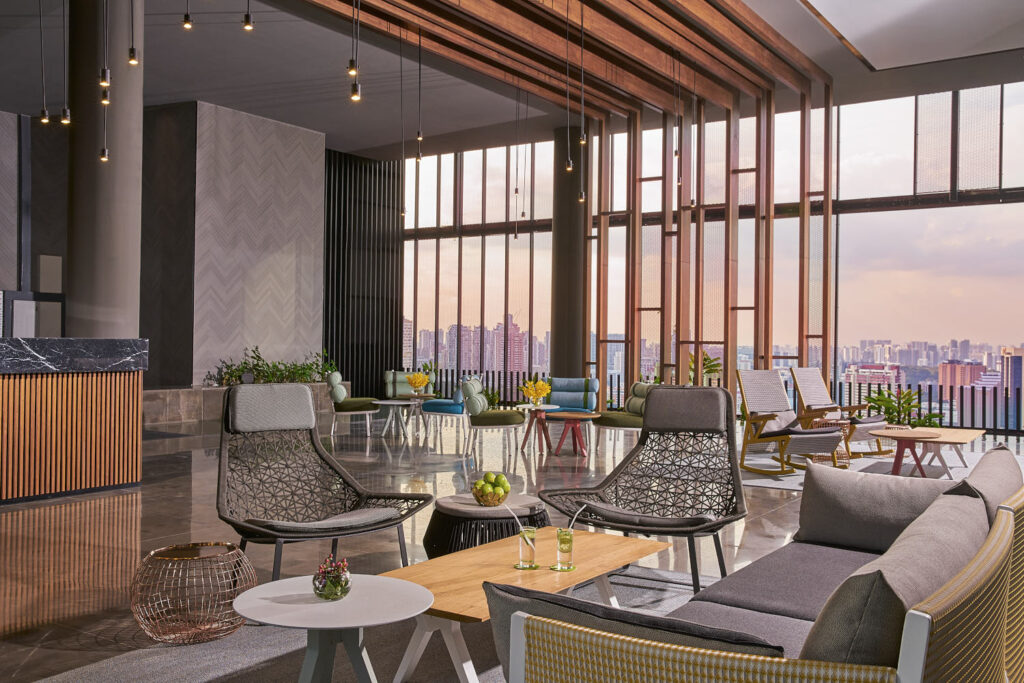 spacious-hotel-lounge-modern-style Modern hotel reception area with open-concept design and city skyline at Oasia Downtown.