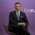 Executive in suit portrait in office environment.