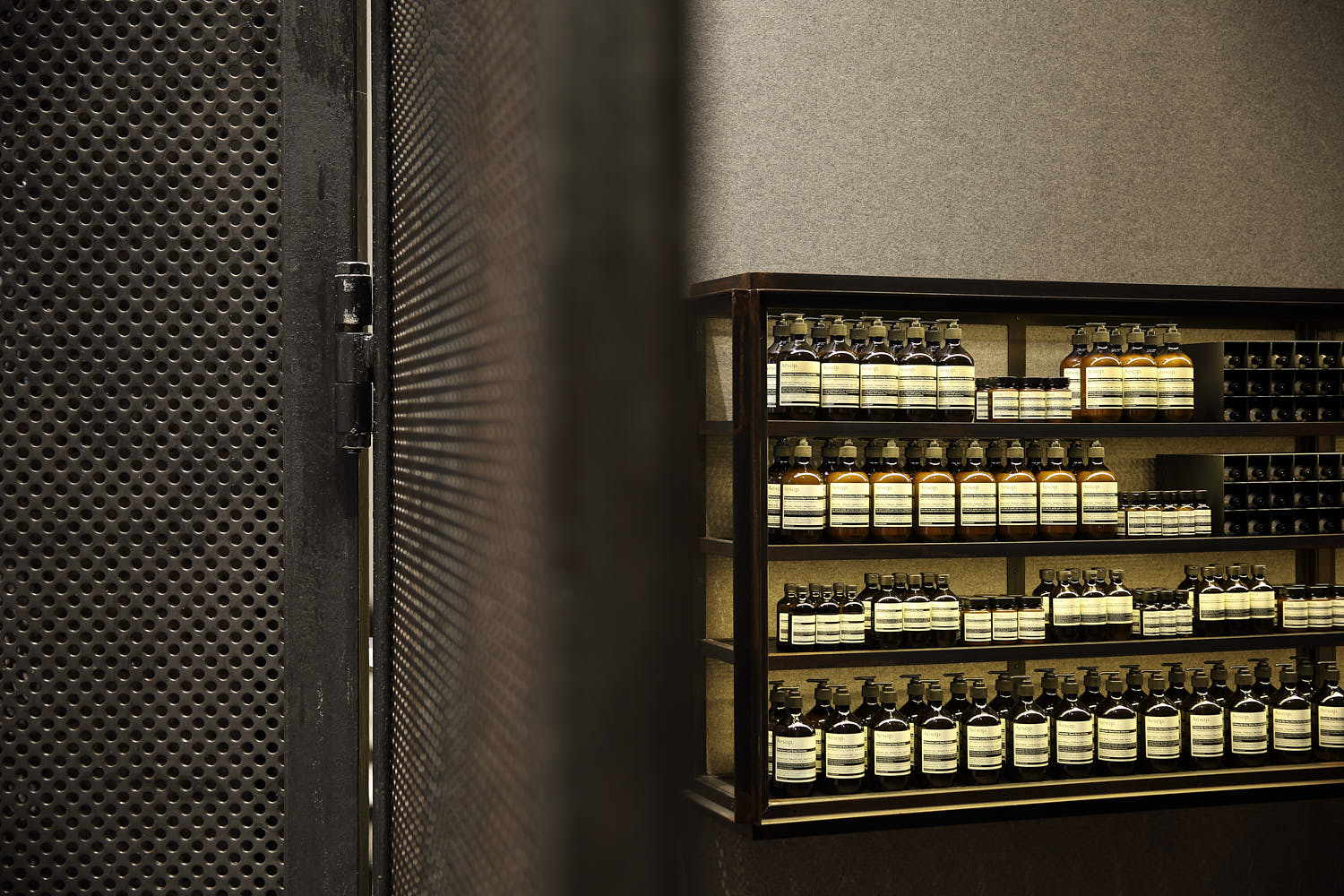 Aesop shelf display featuring raw metal design and neatly arranged skincare products.
