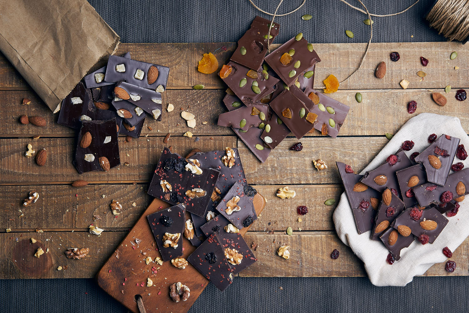 Artisanal chocolate bars from Awfully Chocolate with nuts and dried fruit on a rustic wooden surface.