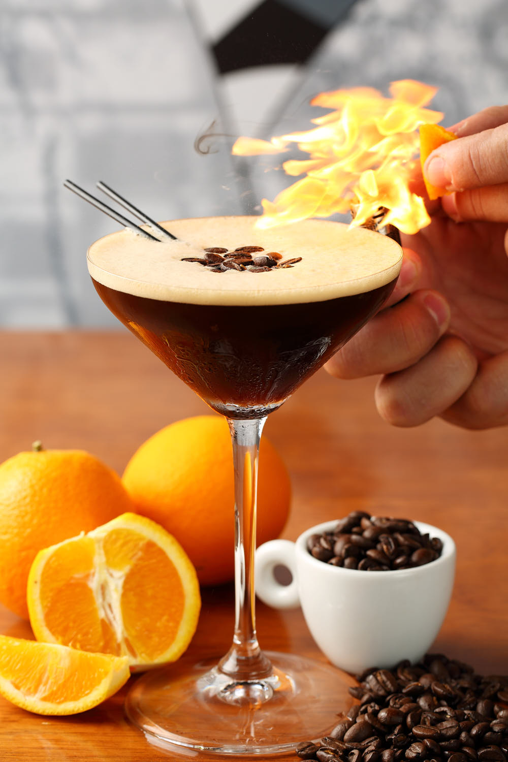 Alcoholic drink with a flame on top, garnished with orange zest and a hint of coffee.