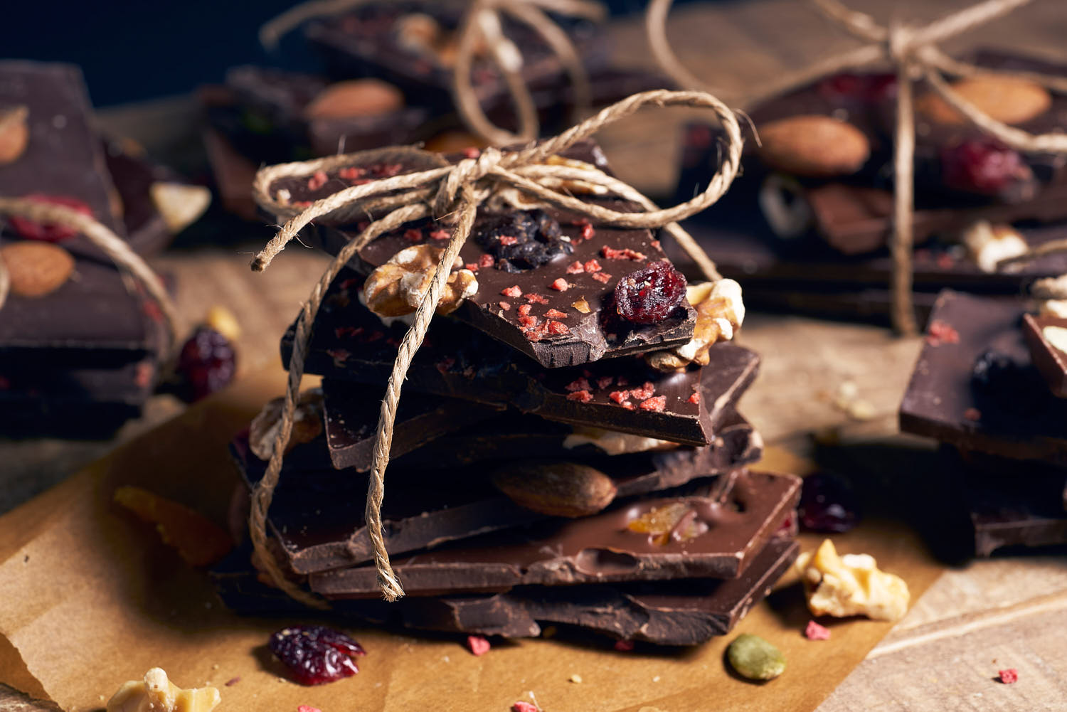 Small slices of dark chocolate tied with twine, resting on a rustic wooden surface.
