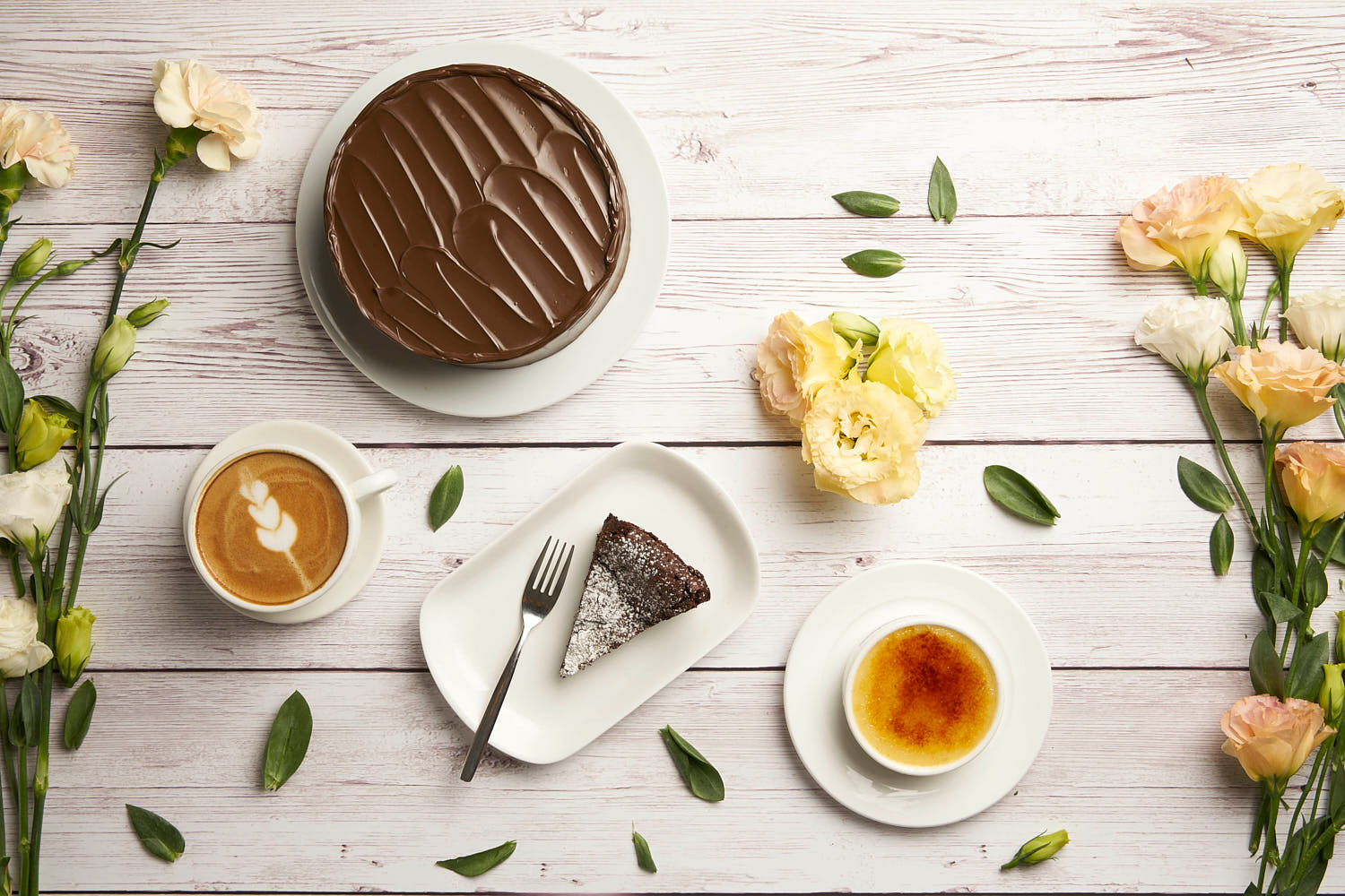 Chocolate cake with glossy ganache and vibrant creme brulee paired with a cup of coffee, shot from above.