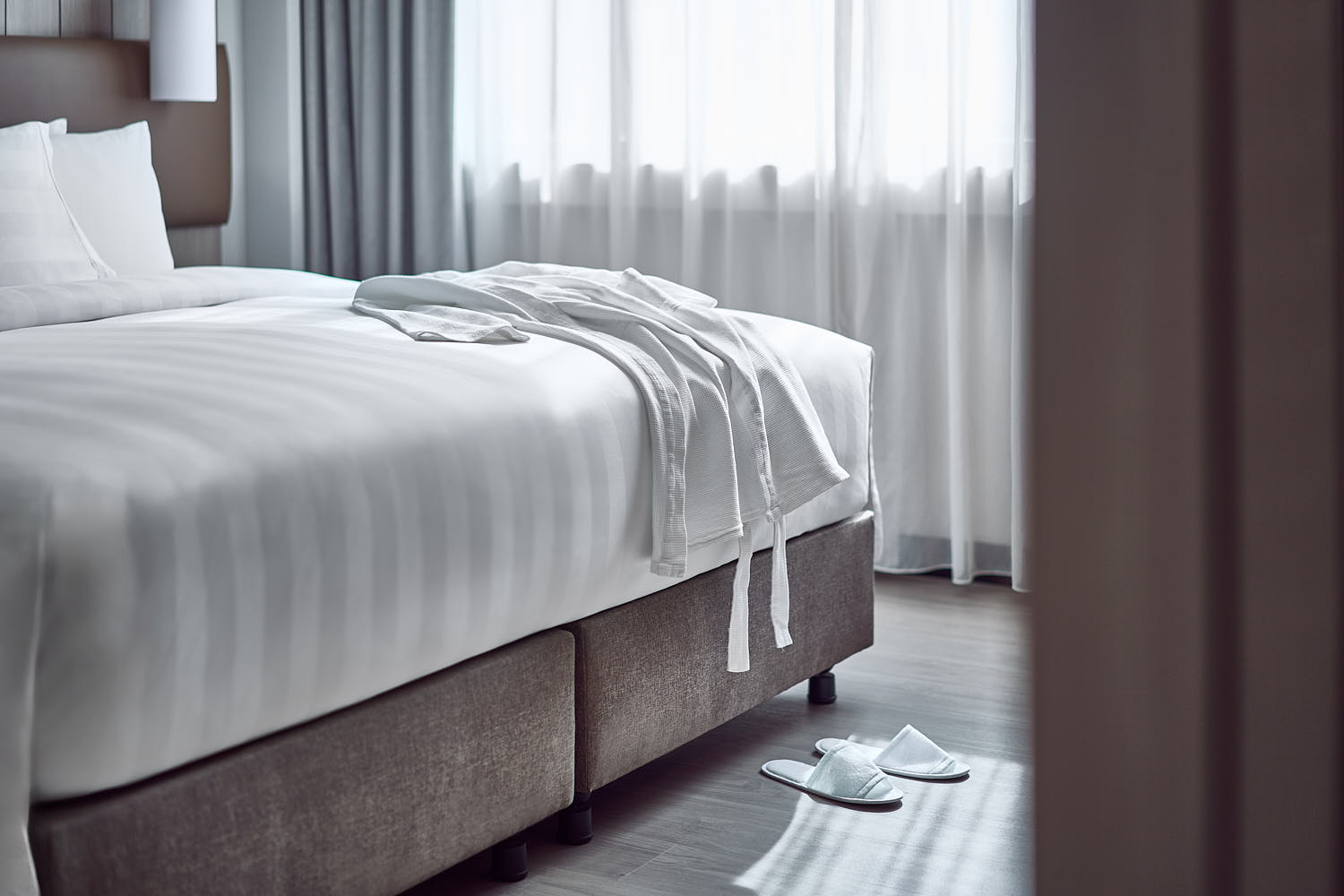 Soft white bathrobe laid out on a hotel bed.