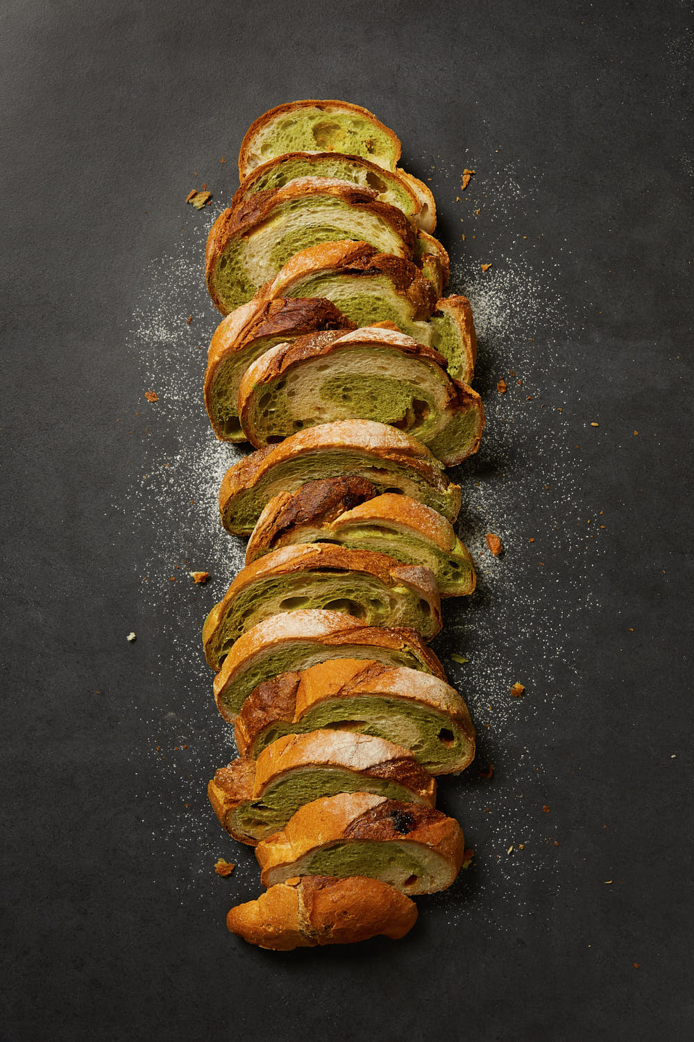 Macha bread styled on granite tile with a dash of icing powder.