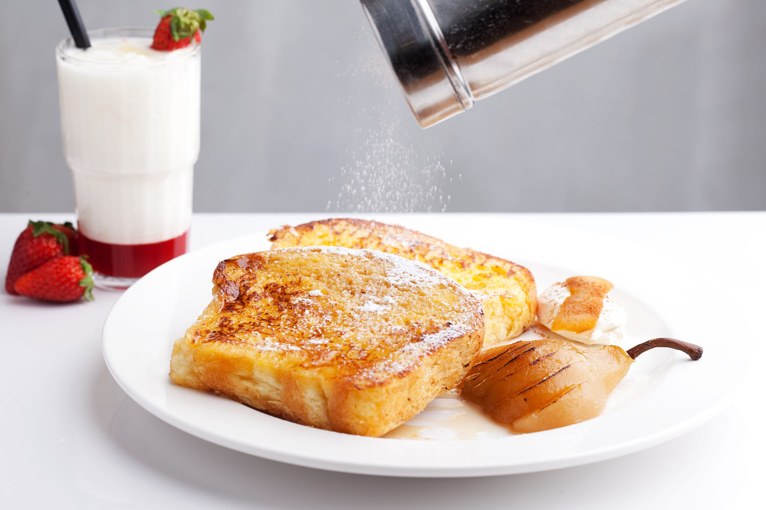 Two slices of iced bread topped with baked pear, paired with a glass of strawberry milk.