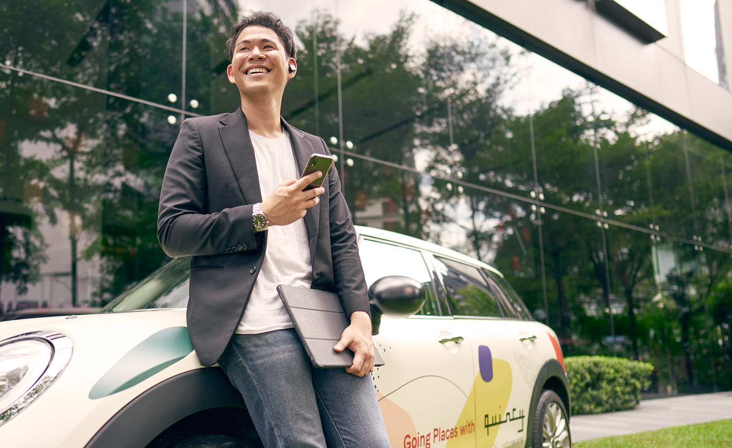 Man engaged in a phone conversation outdoors, casually leaning on his car.