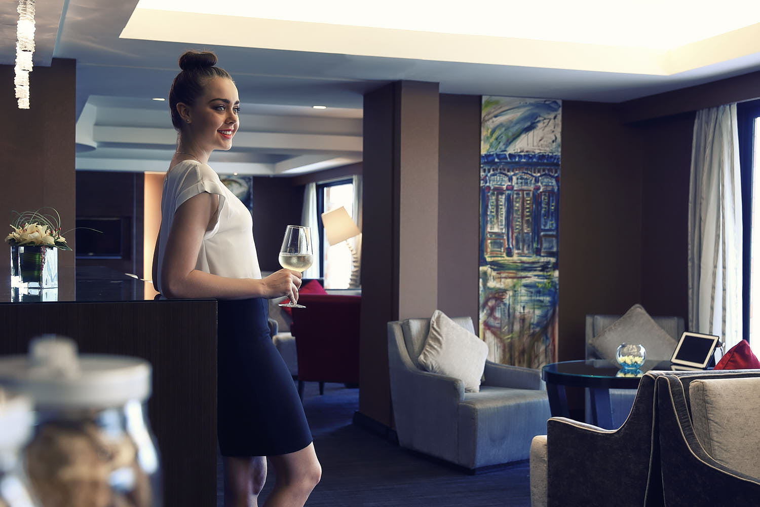 Businesswoman unwinding with a glass of wine in a luxurious hotel lounge.