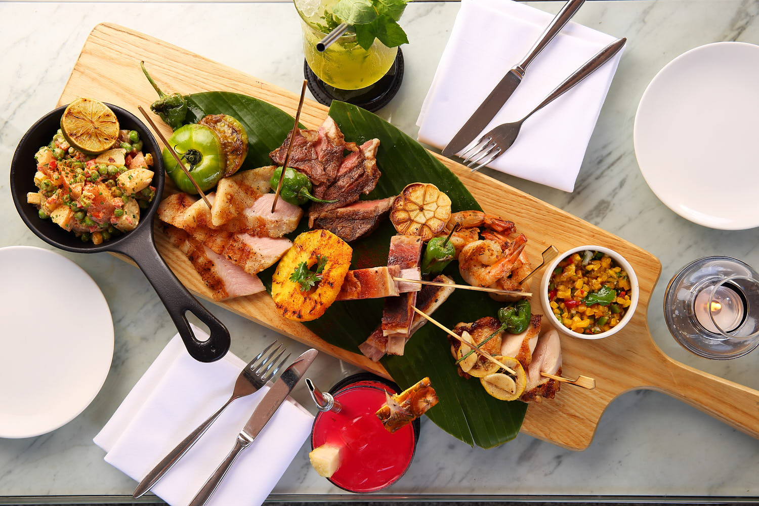 Fine dining platter of premium meats and fresh seafood, artistically plated with microgreens and citrus pearls.