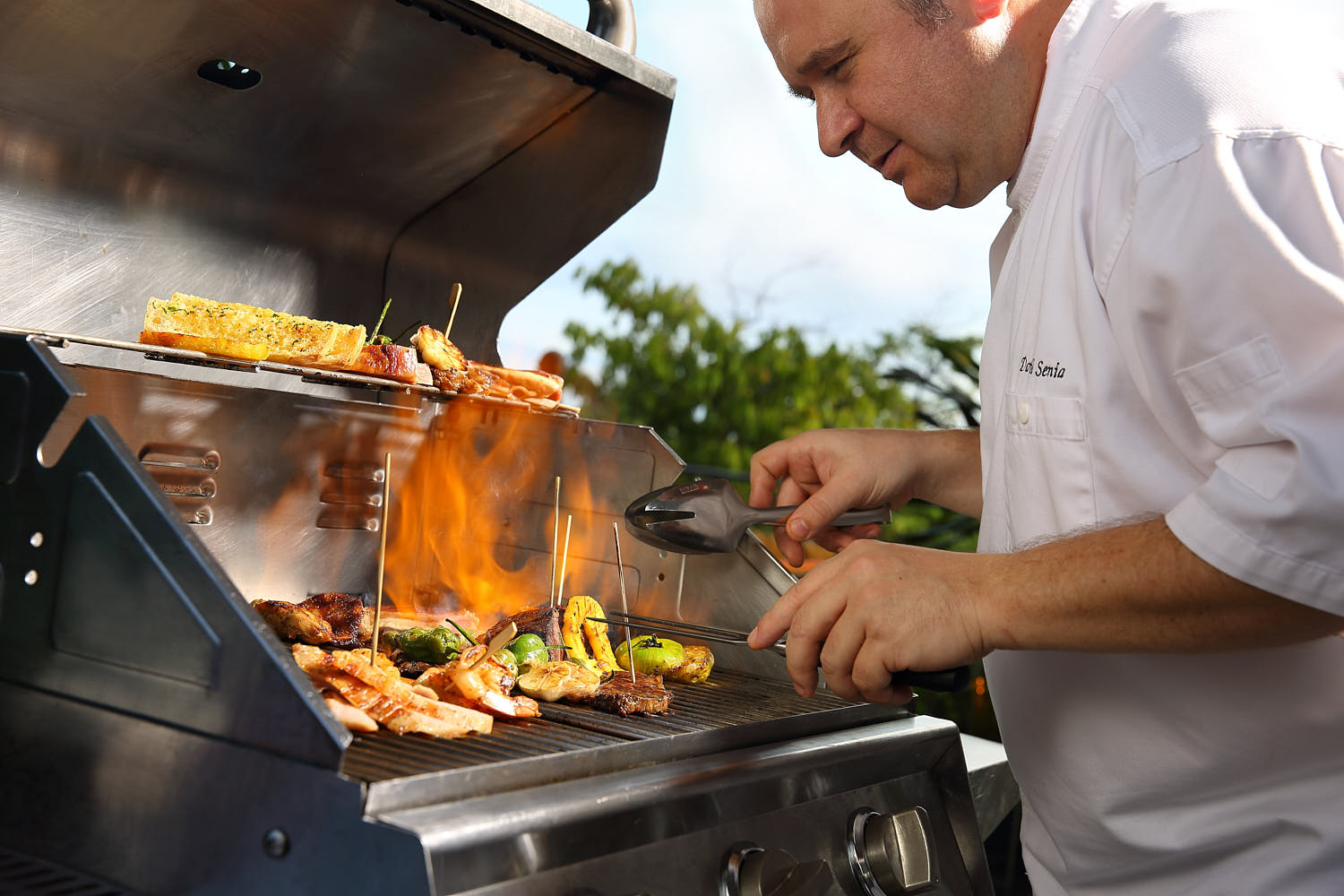 Fine dining BBQ setup at Capella Hotel, showcasing a chef preparing gourmet grilled meats and seafood.