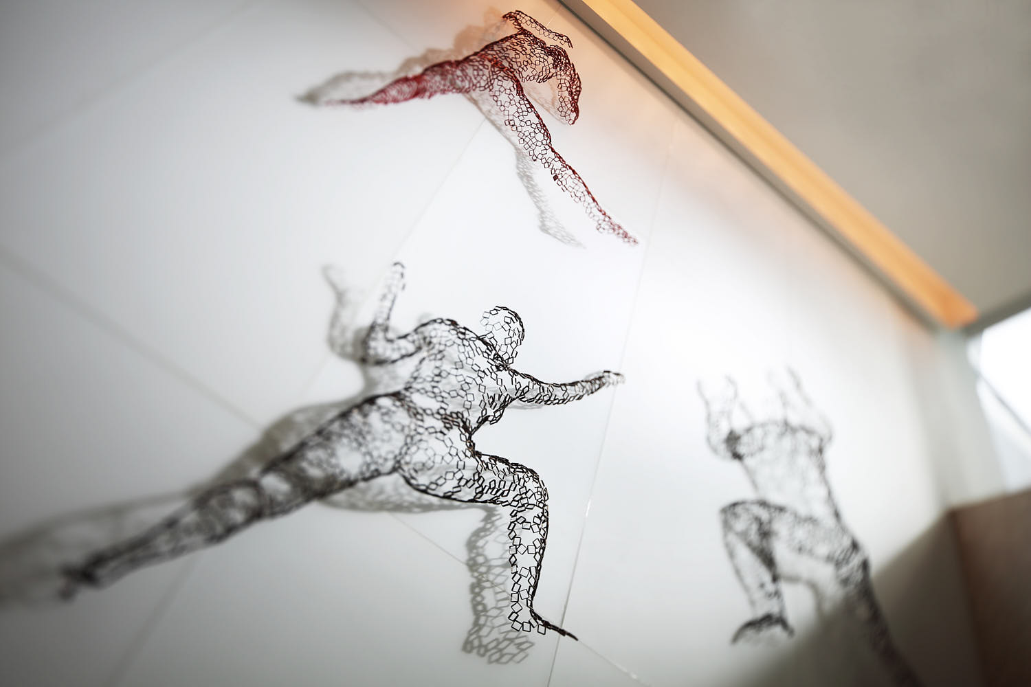 Sculptures of three human figures climbing up a wall on the Capri art feature wall.