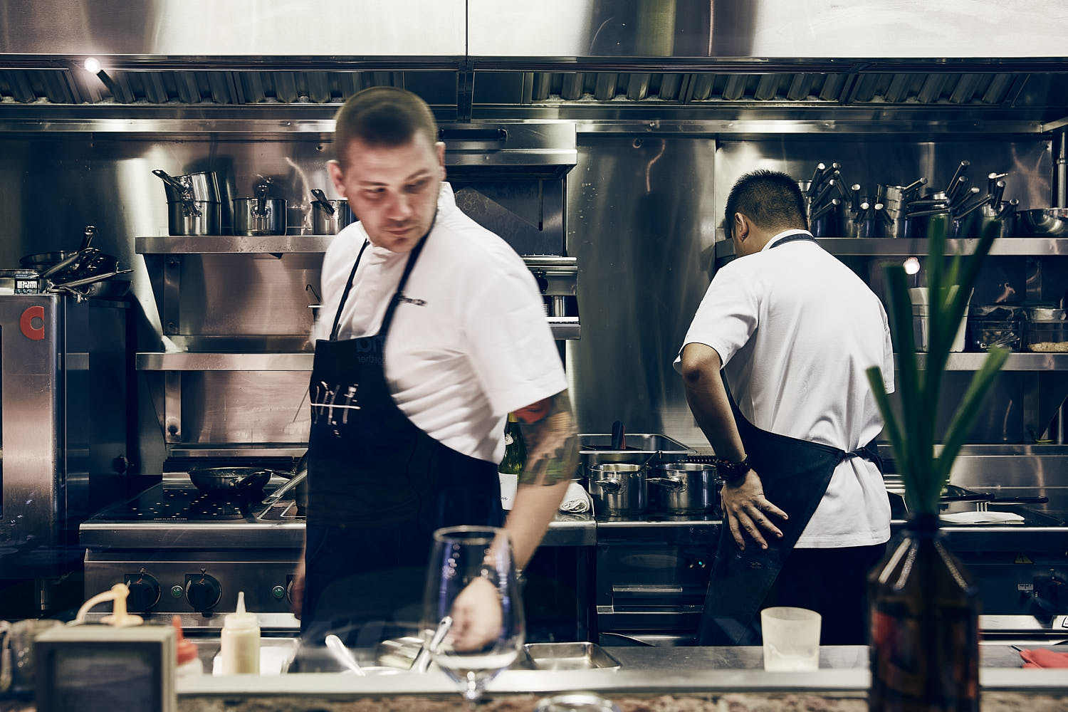 Chef performing cooking technique in a gourmet restaurant kitchen.