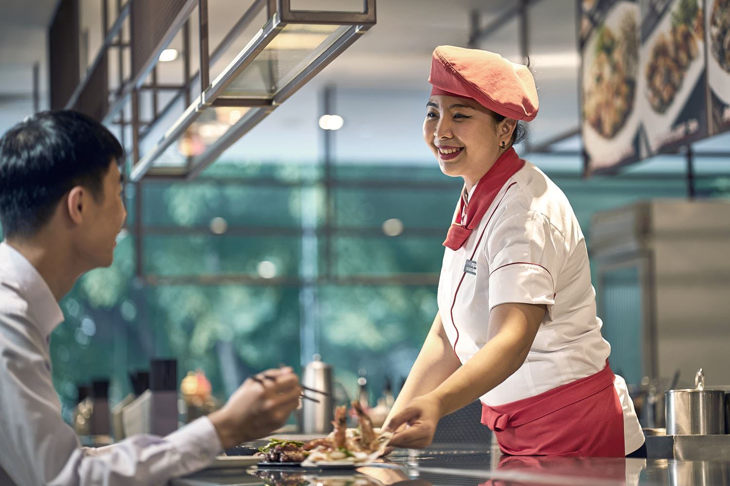 Chef serving sizzling teppanyaki dishes to a guest at a fine dining restaurant.