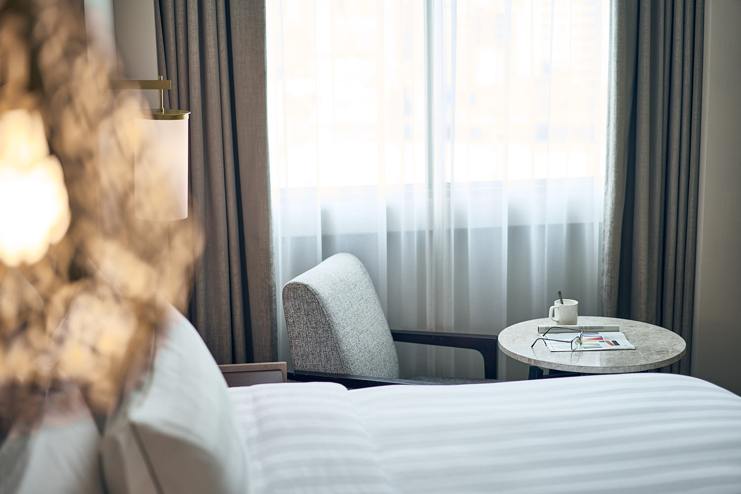 Coffee chair and table with a drink and magazine in a hotel room.