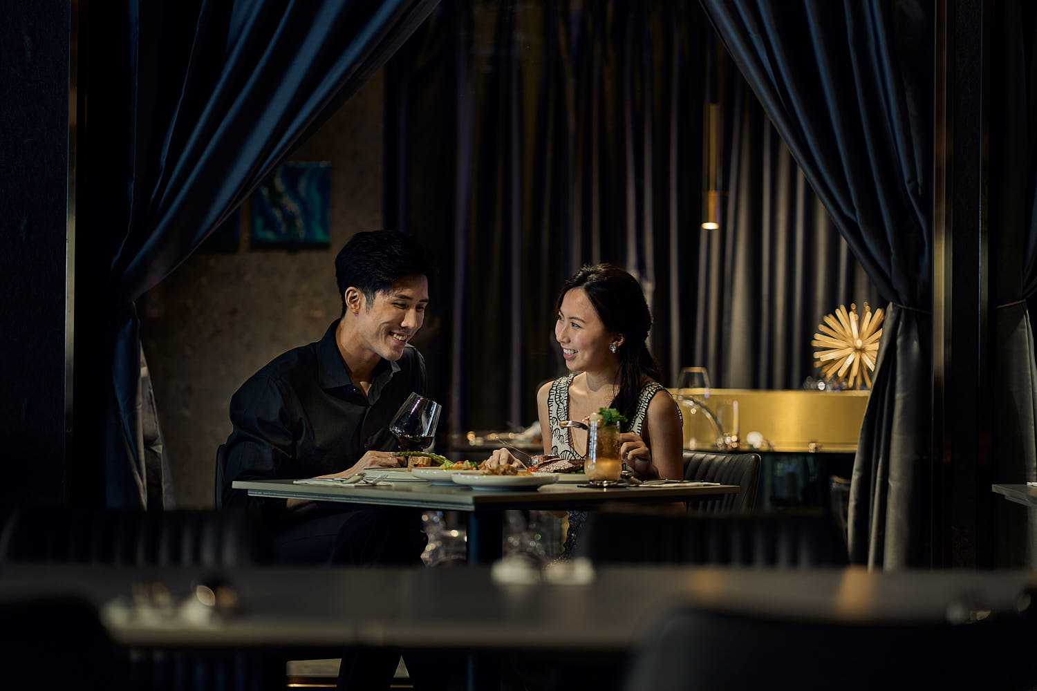 Couple enjoying a romantic candlelit dinner in an elegant restaurant setting.