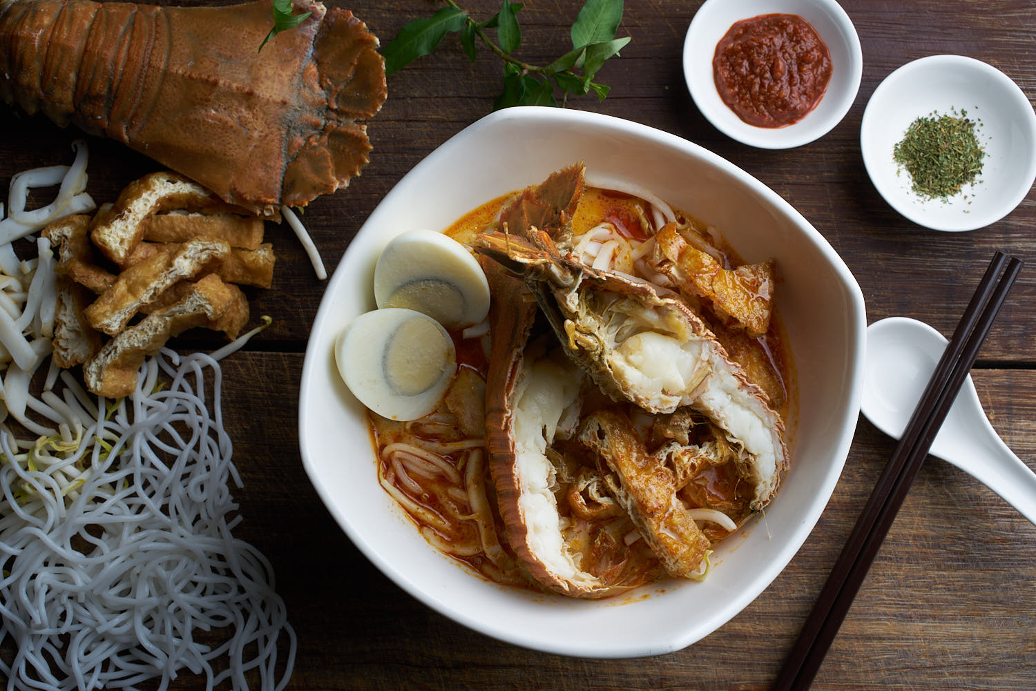 Top view of crayfish laksa with ingredients on rustic board at Grand Mercure Hotel.