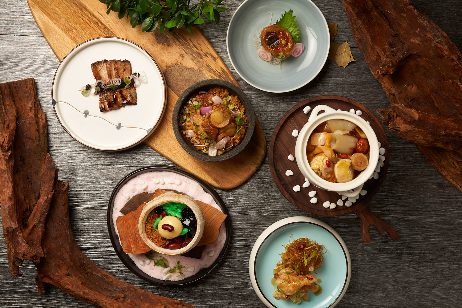 Top-down view of Crystal Jades's signature dishes with fried rice, sliced pork, abalone, dessert in a coconut and soup.