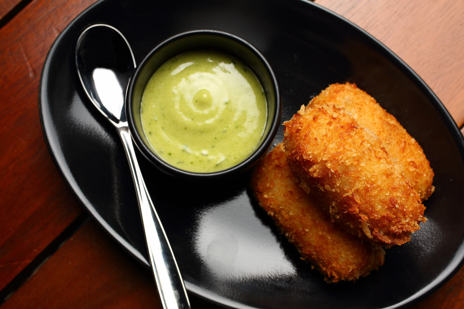 Top down shot of a deep fried potato finger food with sauce.