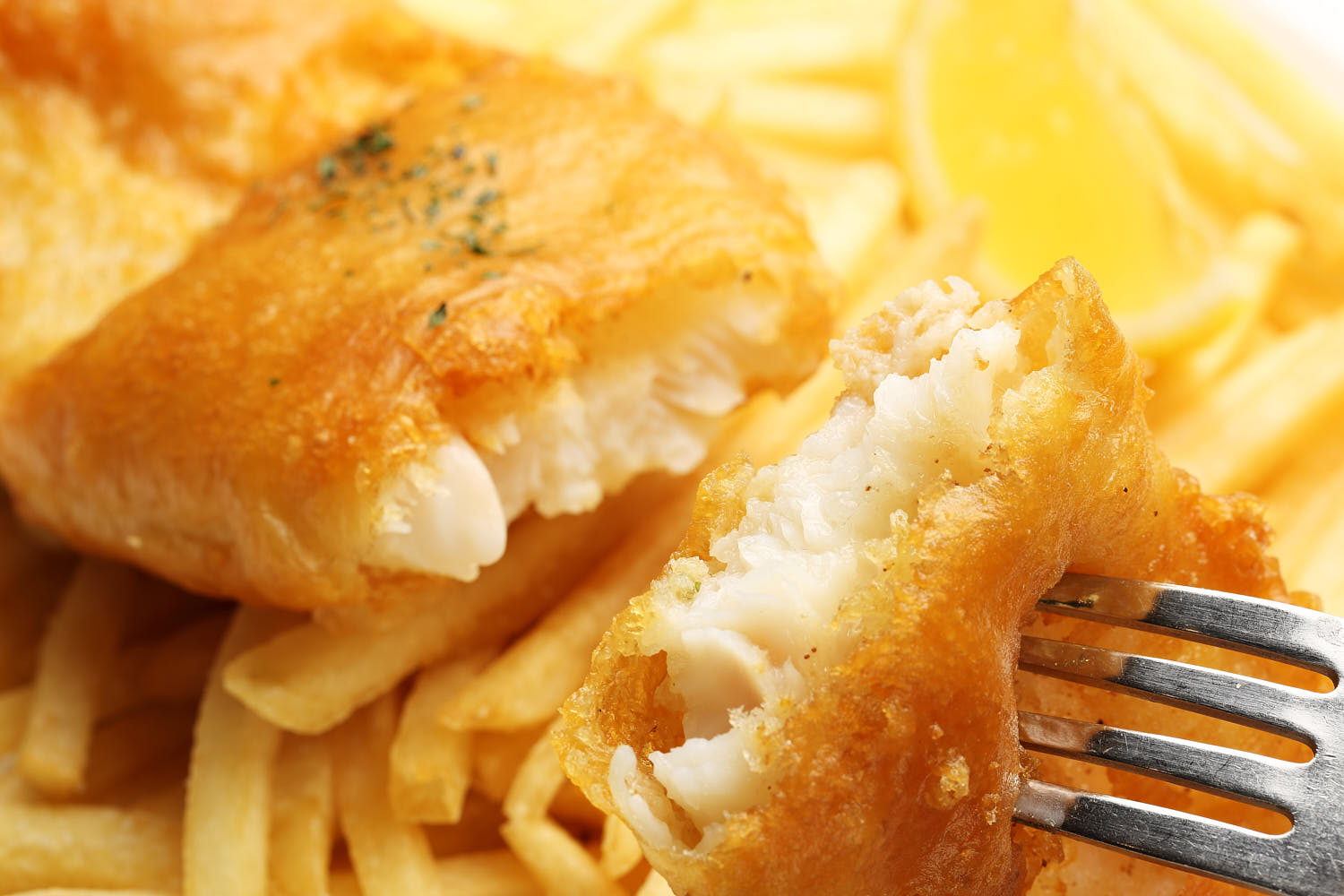 Macro shot of fish and chips revealing tender, fresh fish inside.