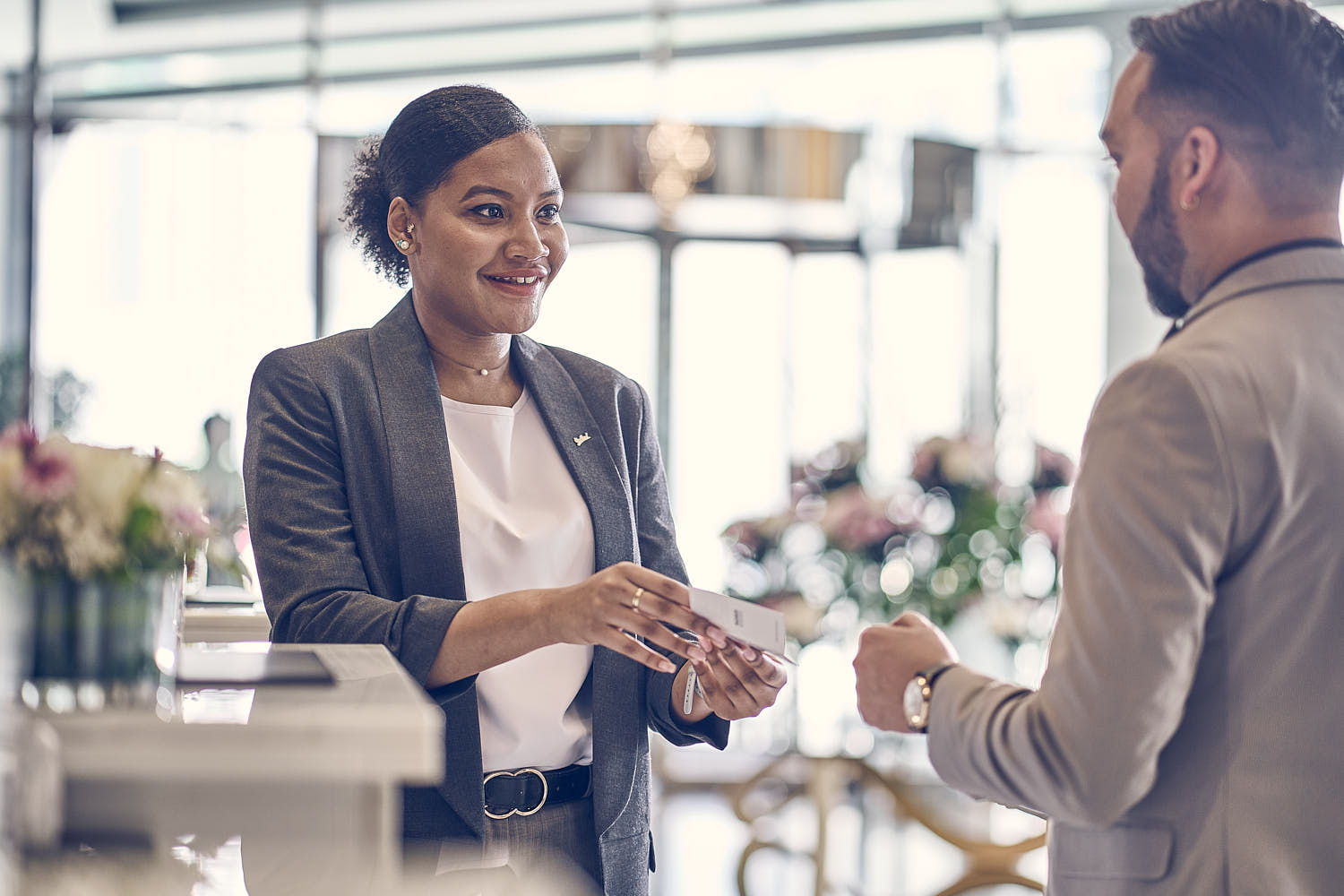 Friendly front desk agent smiling while assisting a hotel guest with check-in.