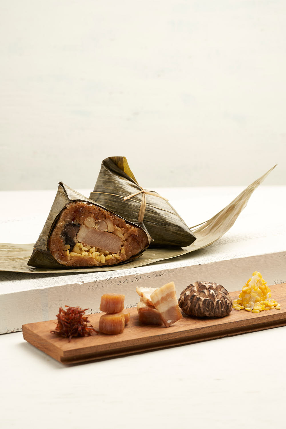 Steamed glutinous rice dumpling with savory mushrooms, dried scallops, and tender pork, wrapped in a fragrant bamboo leaf.