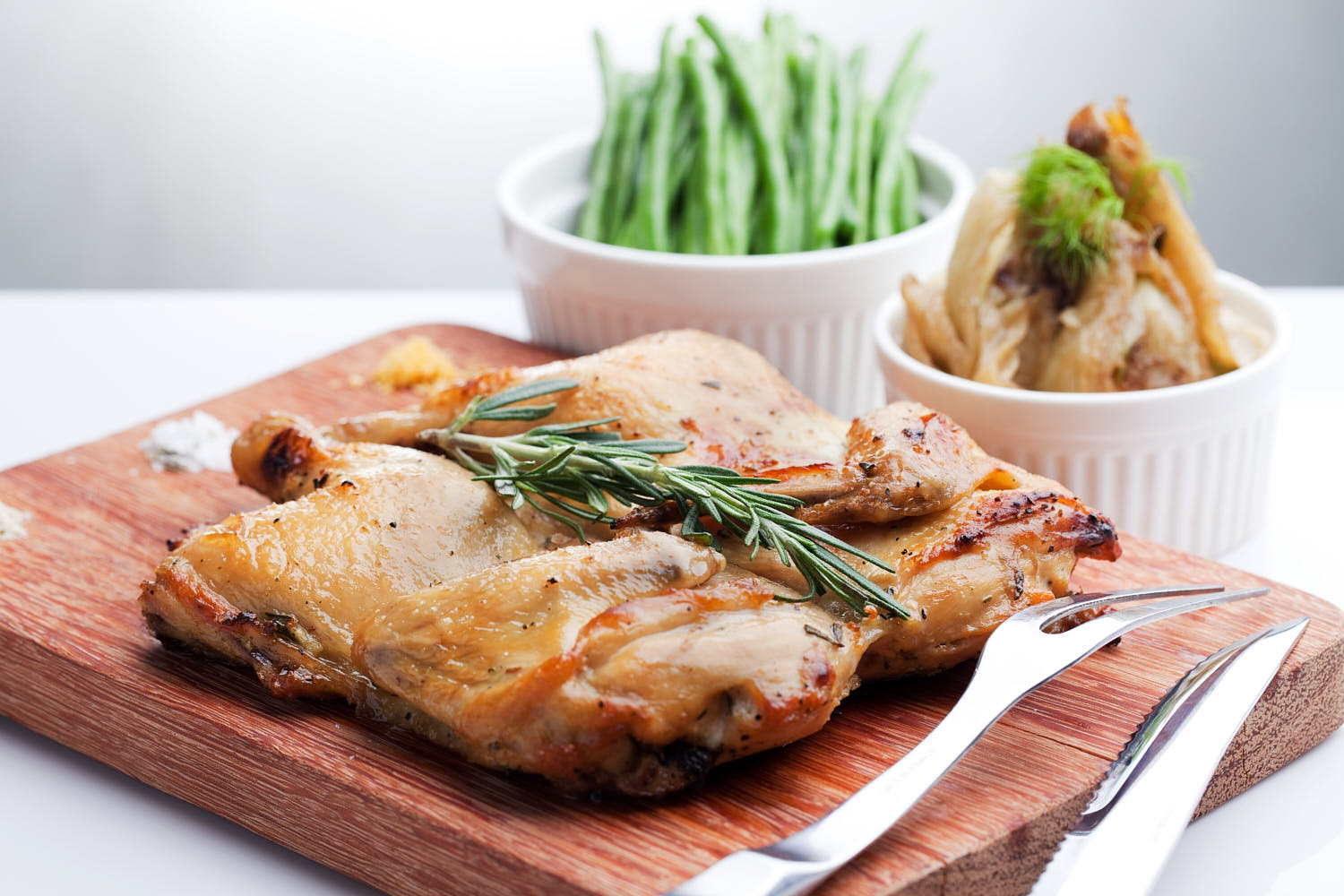 Golden roasted chicken with crispy skin, served with fresh herbs and roasted vegetables on a rustic plate.