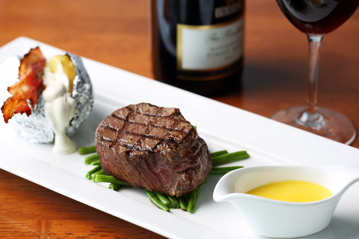 Thick, juicy beef steak served with a baked potato topped with crispy bacon and sour cream.