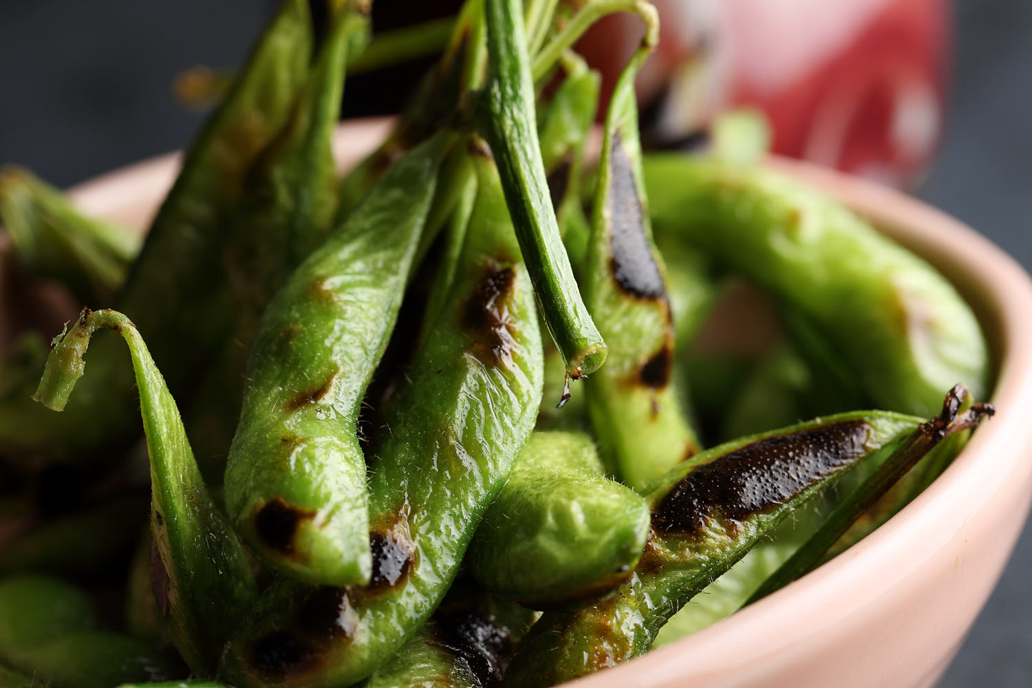 Close-up of charred edamame pods, perfectly grilled and garnished with sea salt.
