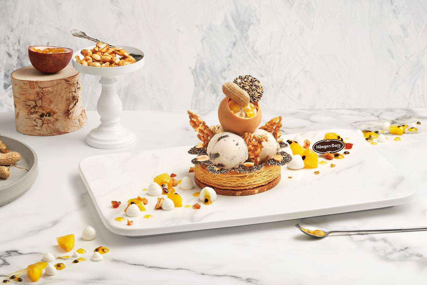 Elegant Häagen-Dazs ice cream scoop with delicate fruit art on a white marble surface.
