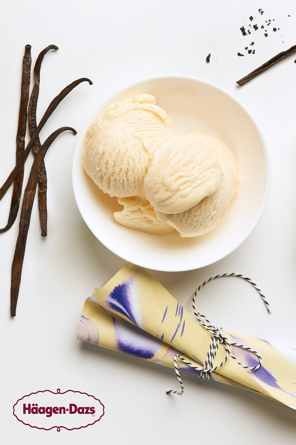 Single scoop of Häagen-Dazs vanilla ice cream in a white bowl, garnished with vanilla beans.