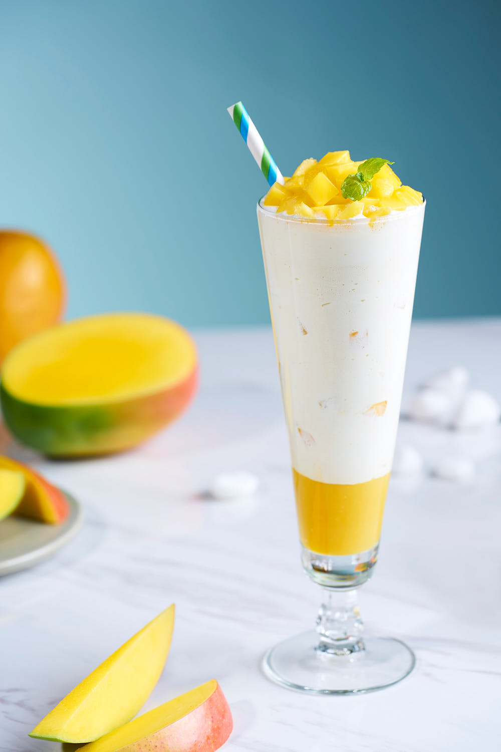 Refreshing mango shake in a tall glass, topped with a scoop of Häagen-Dazs mango ice cream and cubes of fresh mango.