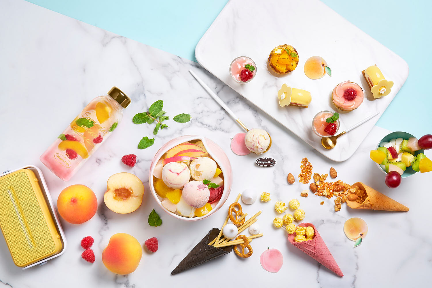 Assorted Häagen-Dazs ice cream in a bowl, with cones filled with toppings, bite-sized tarts, and mini layered cup desserts.