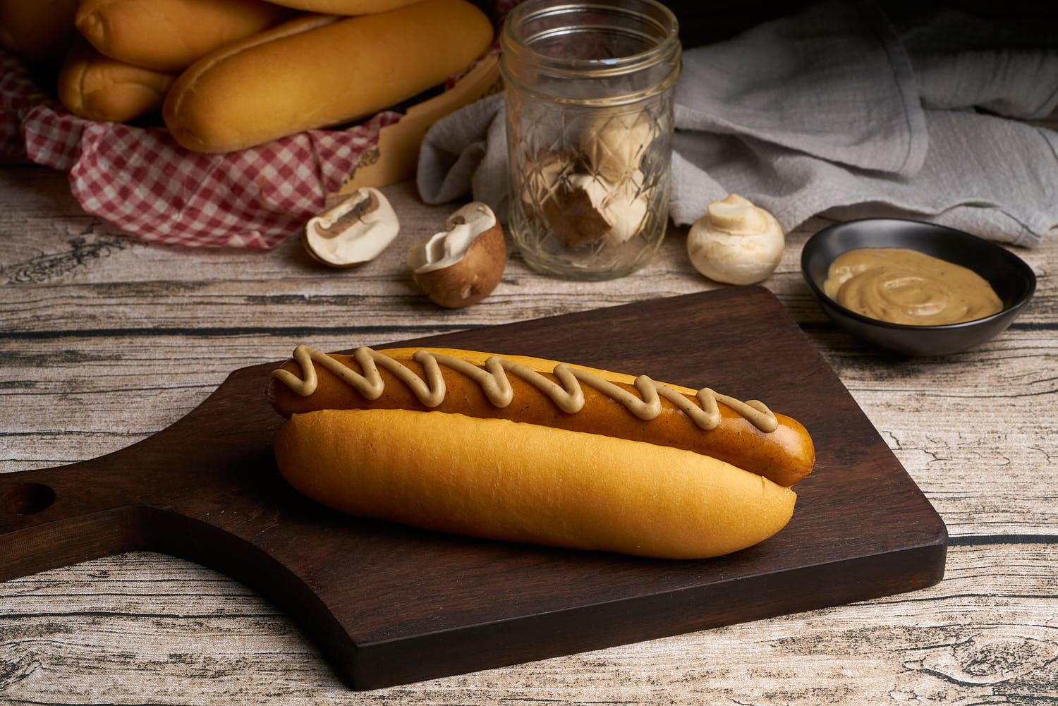 Hot dog drizzled with mushroom sauce on a wooden top.