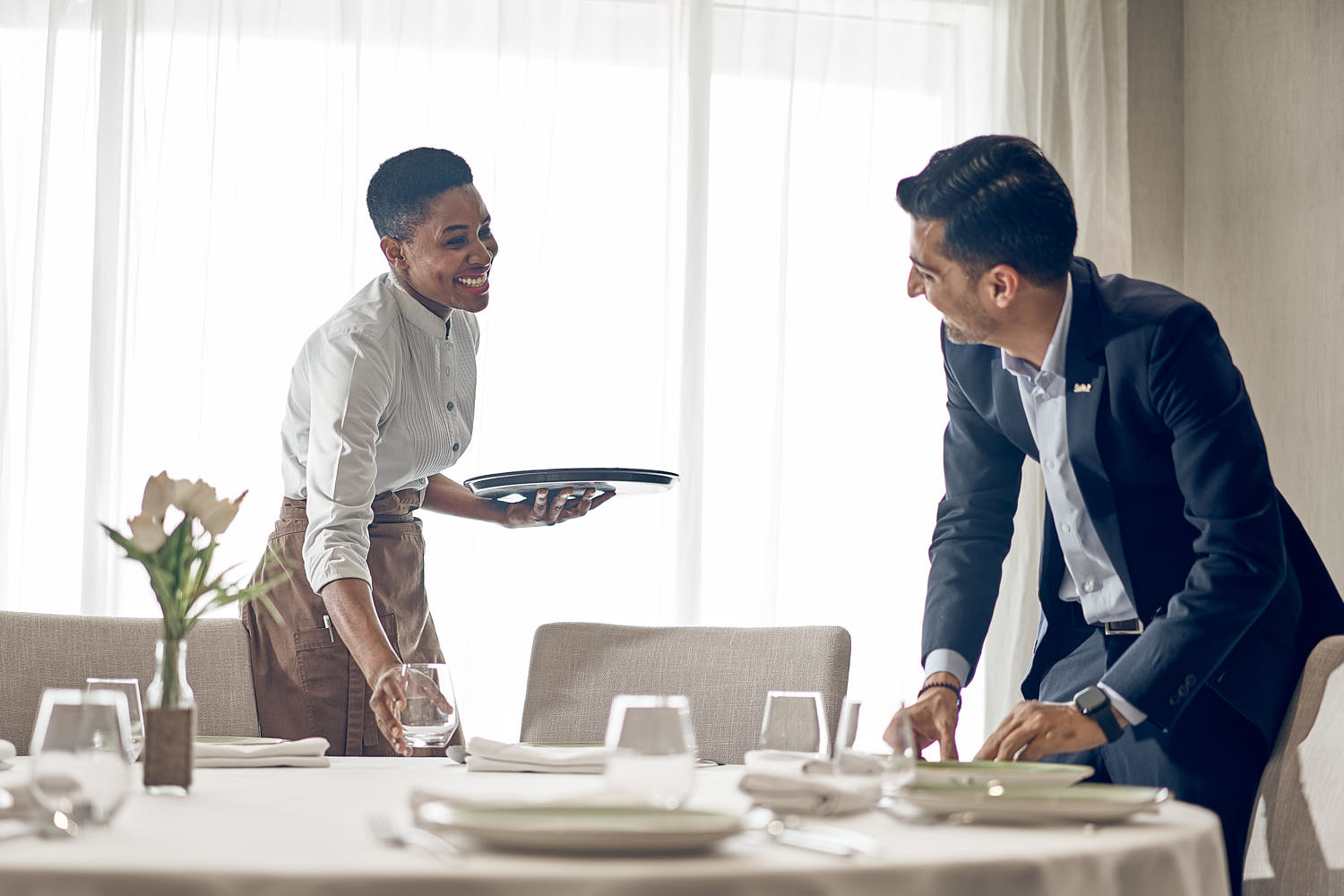 Banquet team at a hotel setting up tables and decorations in a well-designed event hall.