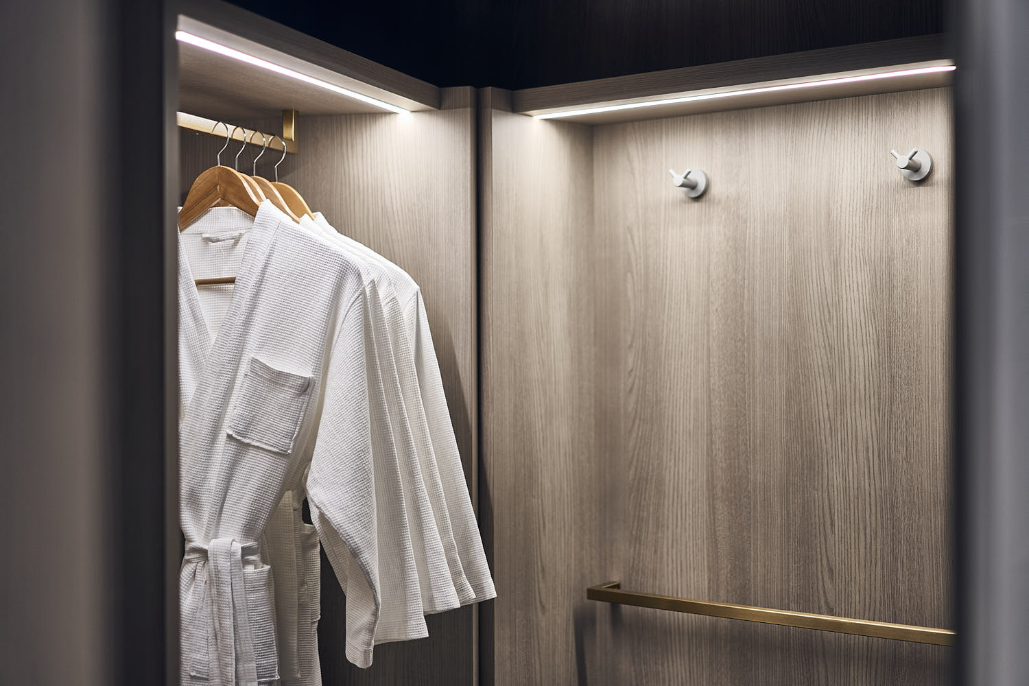 Open hotel room closet with neatly hung bathrobe.