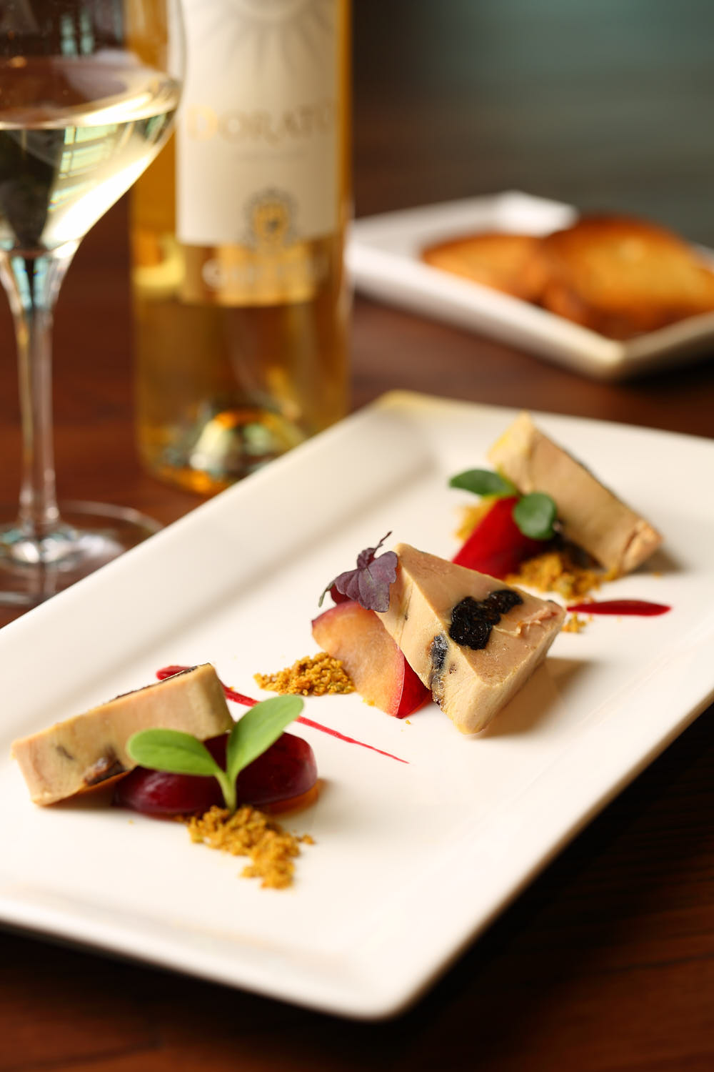 Foie gras served with roasted peaches, finished with a touch of port wine reduction and edible flowers.