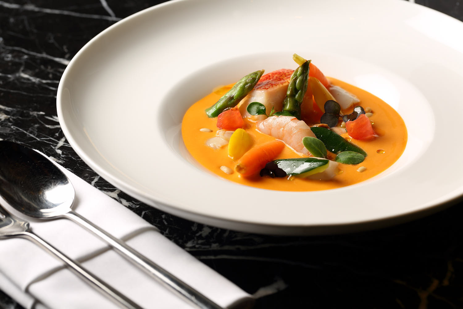 Hearty seafood bisque with prawn, fresh fish, and cream, garnished with fresh herbs.