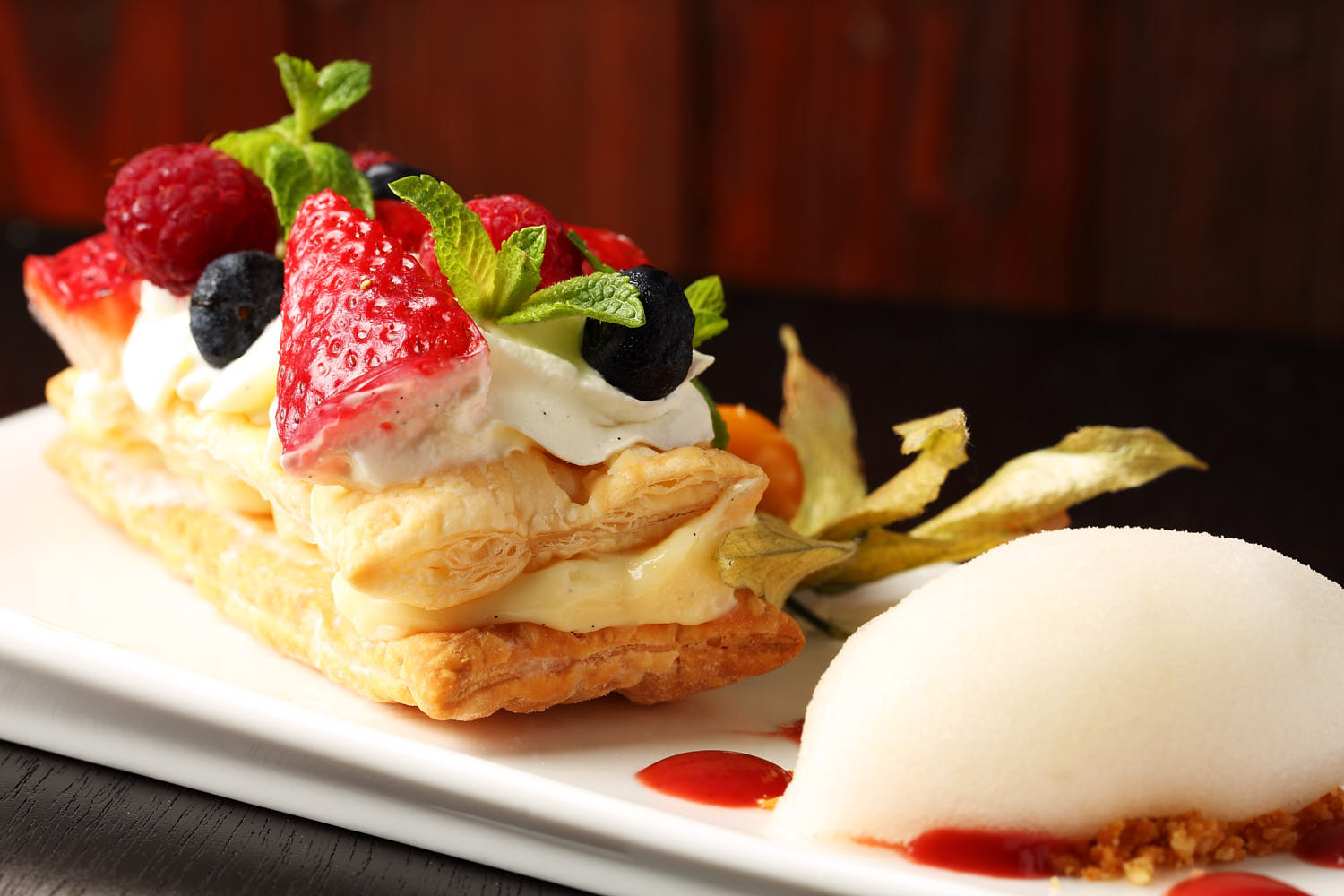 Elegant pastry filled with smooth cream, topped with fresh berries and a refreshing scoop of sorbet.