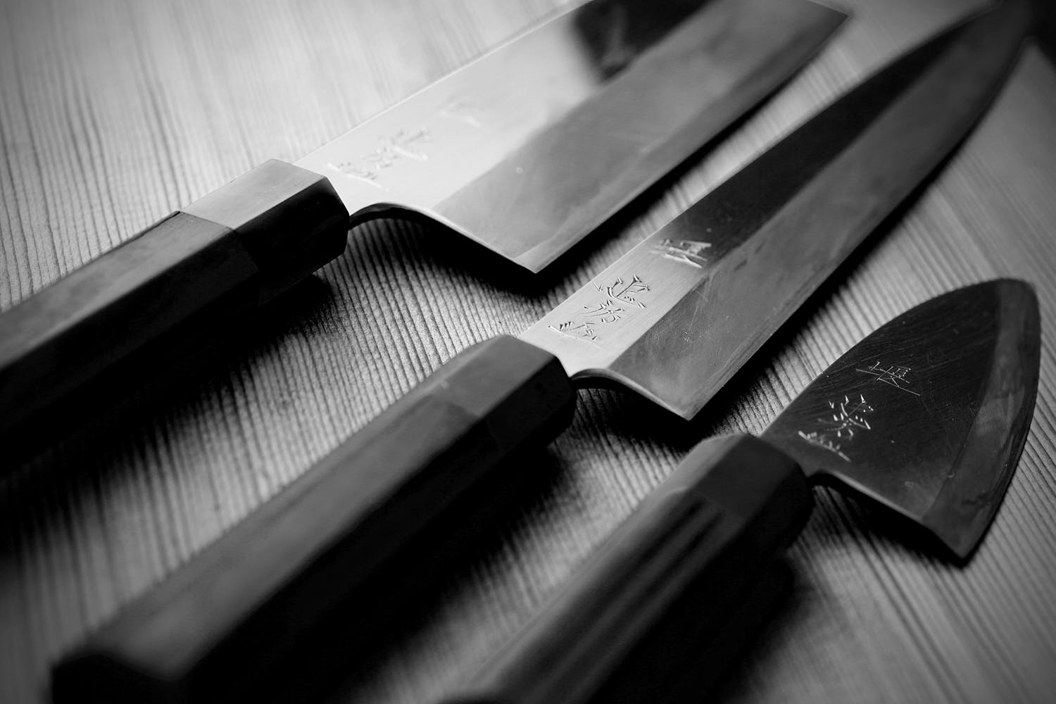 Set of three Japanese culinary knives in black and white artistic composition.