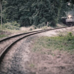 KTM train approaching from a distance on a long winding track surrounded by greenery at Commonwealth, Singapore.