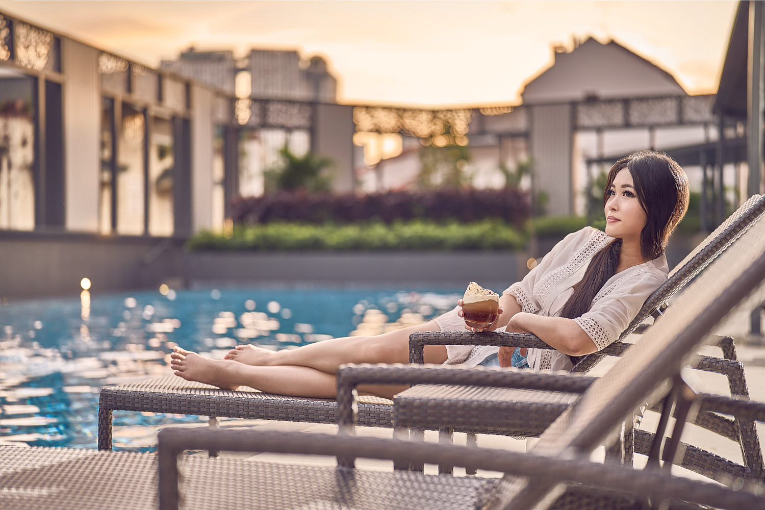 Hotel guest unwinding at a luxury resort pool, enjoying sunset ambiance.