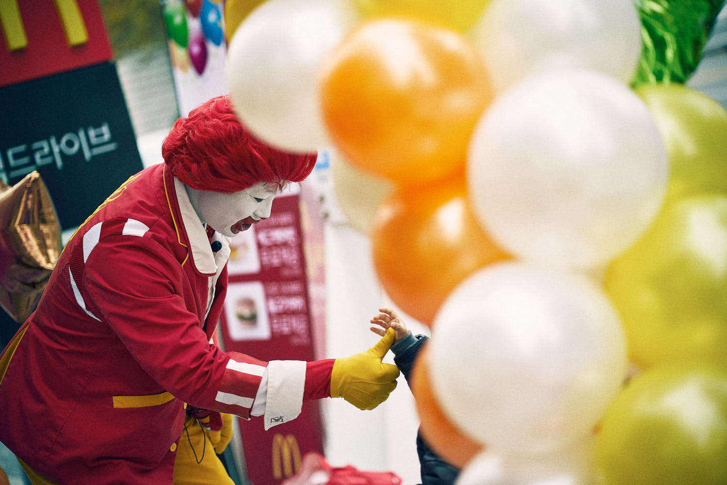 Young children having fun in McDonald's play area, joined by Ronald McDonald.