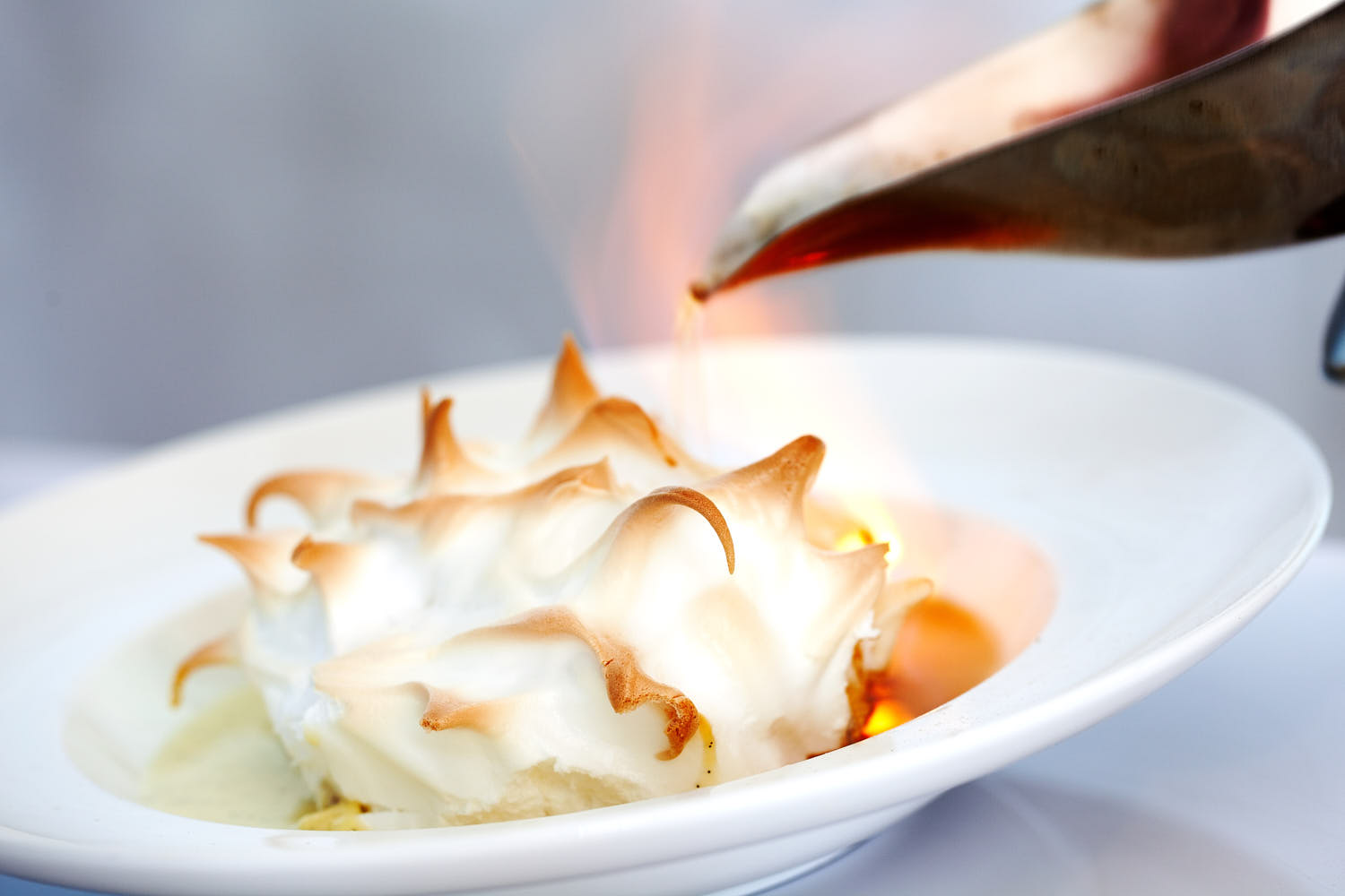 Gourmet meringue dessert with caramelized flames and a golden, crispy exterior.