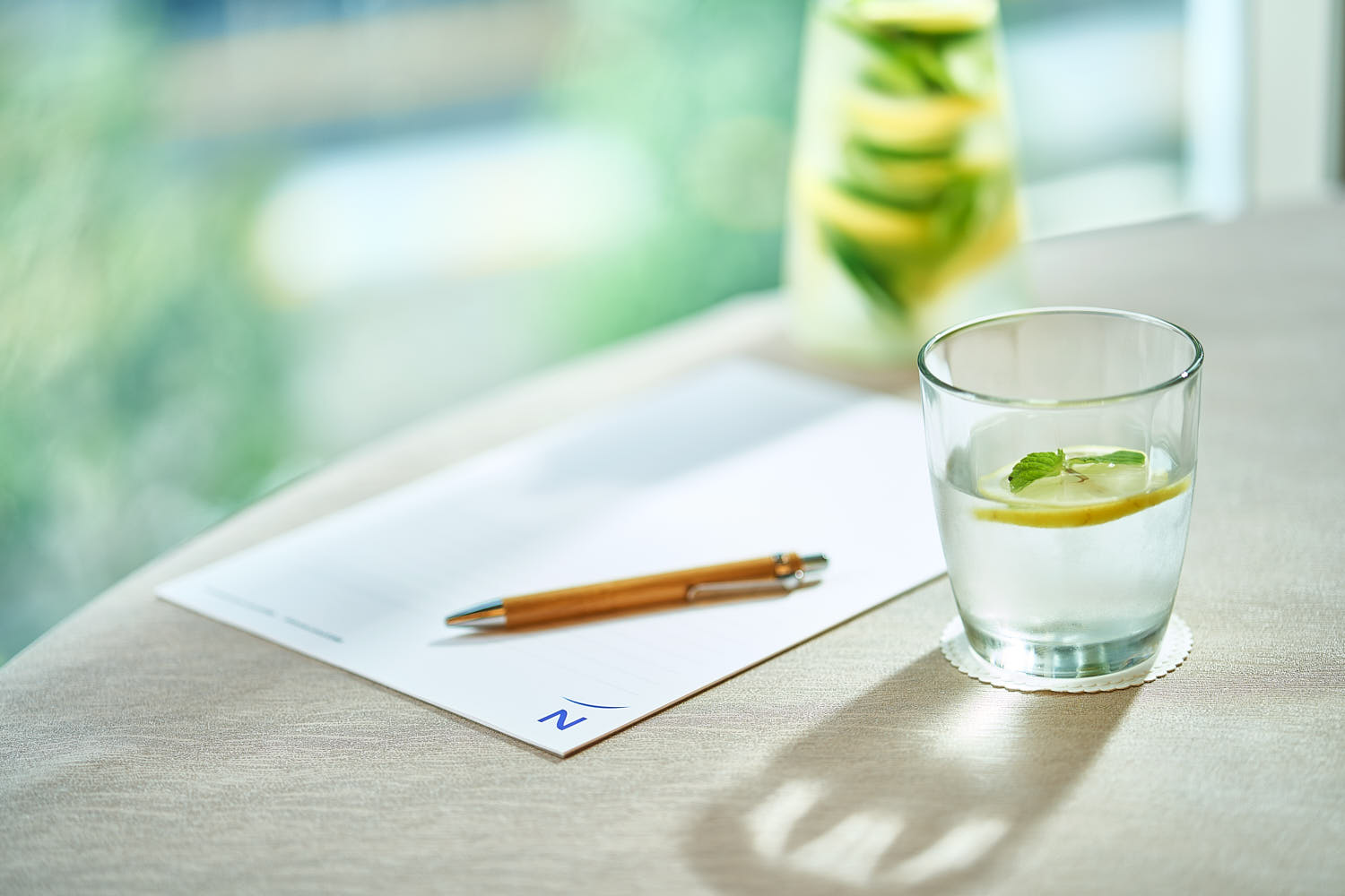 Close-up of lemon and mint infused water with notepad and pen on table at Novotel.